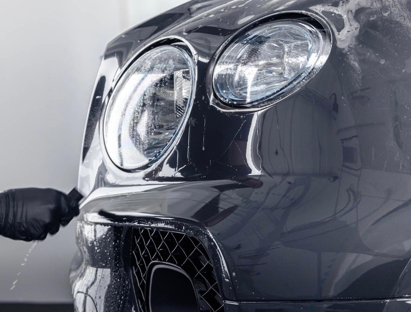 Close-up of a car's front bumper and headlight during PPF application